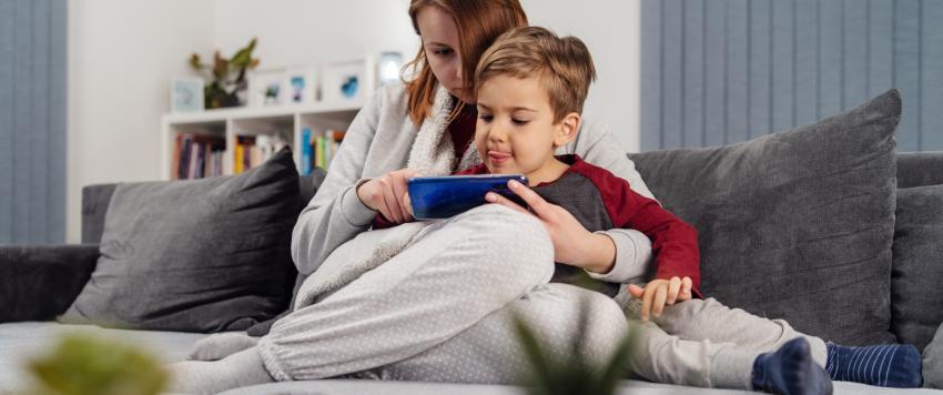 أم تجلس بجوار ابنها الذي يتعلم باستخدام الهاتف المحمول