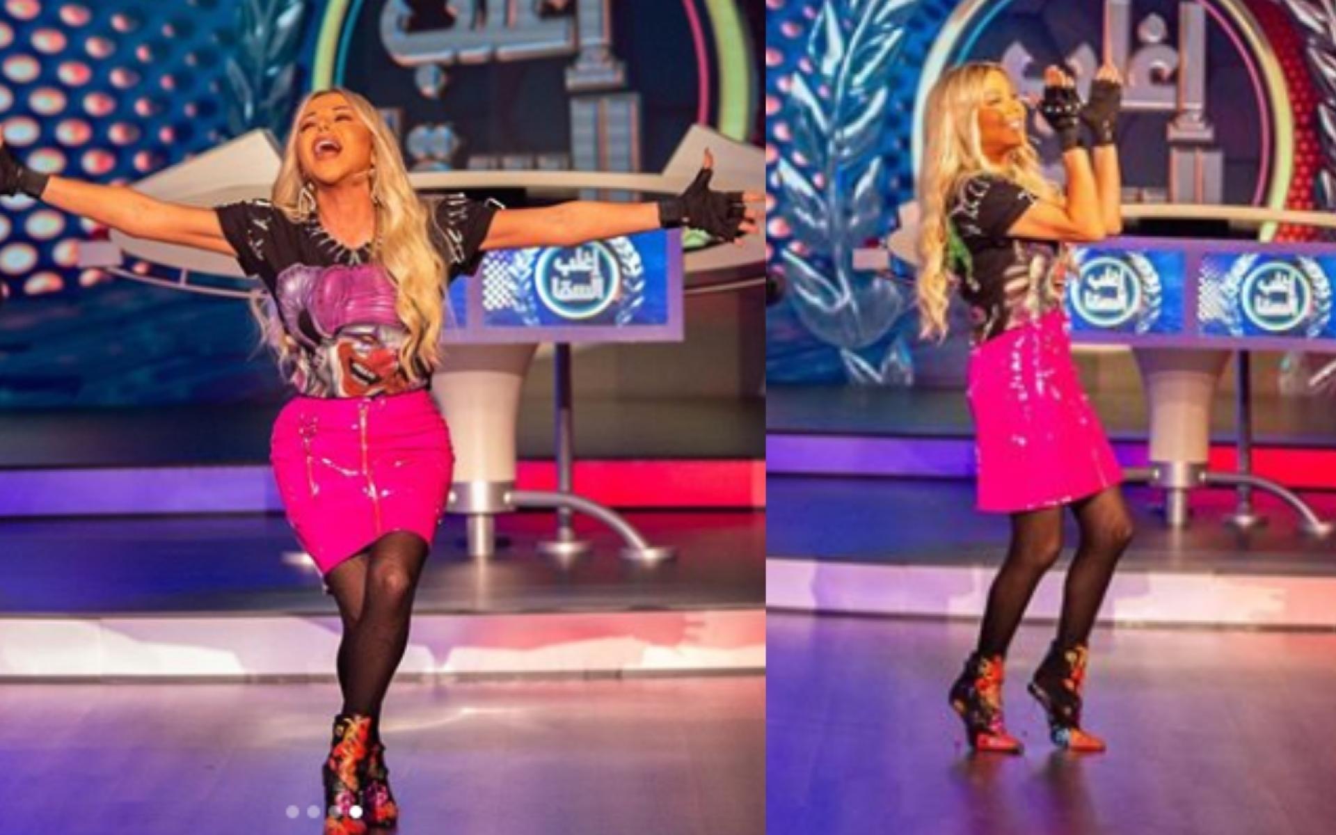 تنورة جلد باللون زهري حريء مع توب أسود وإكسسوار يشمل قفازات باللون الأسود