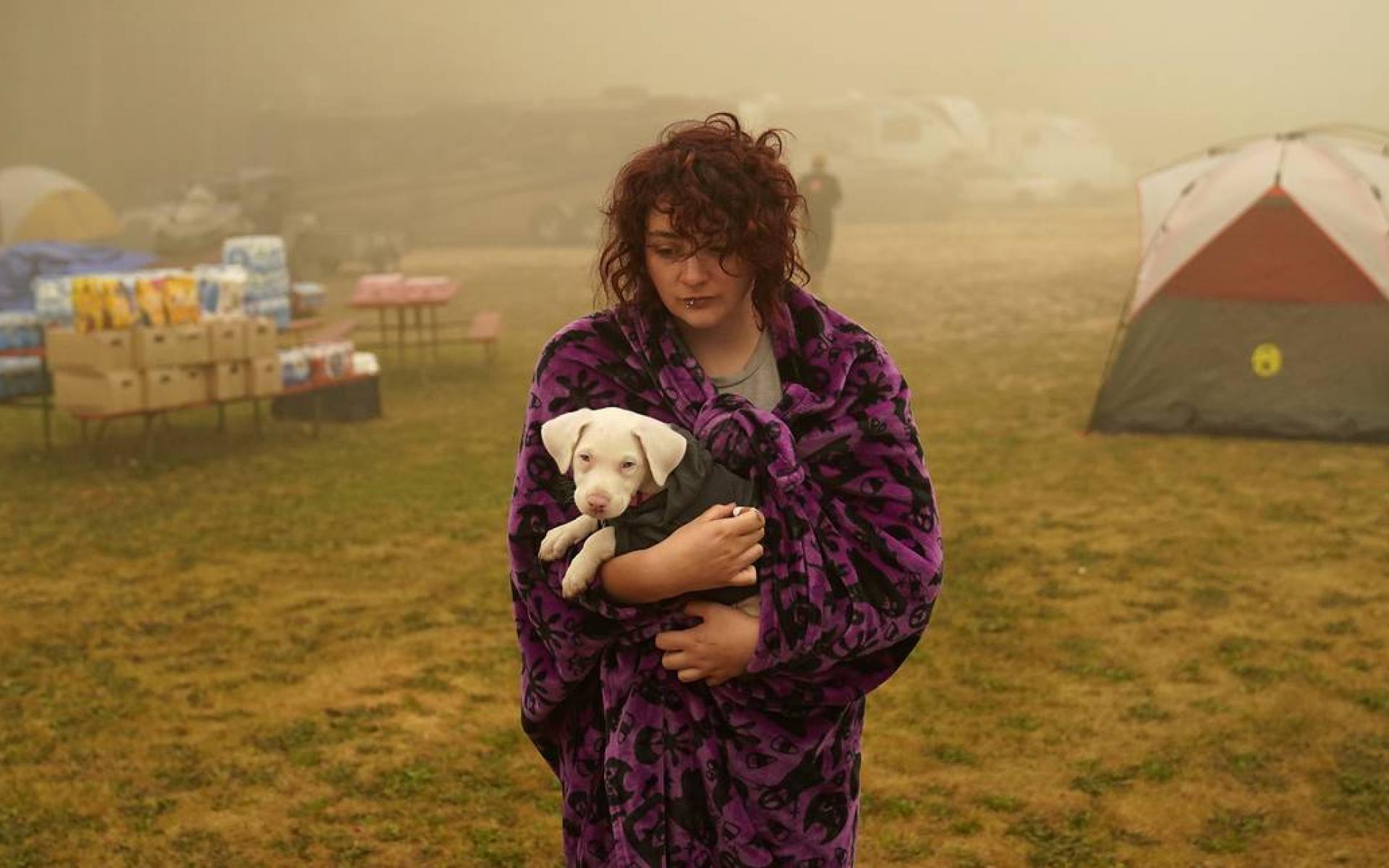 شايان سمرز تحمل كلبها بعد عدة أيام من الإقامة في خيمة بمركز الإجلاء. تم إجلائها من بالقرب من مولالا التي كانت مهددة بنيران ريفرسايد